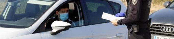 Pla mitjà d'un agent de la Guàrdia Urbana mirant el paper justificant de mobilitat d'un conductor a un control a la N-230 direcció Lleida