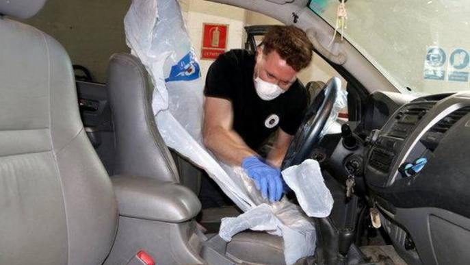 Un operari col·locant les proteccions a l'interior d'un vehicle com al seient, volant, canvi de marxes i fre de mà