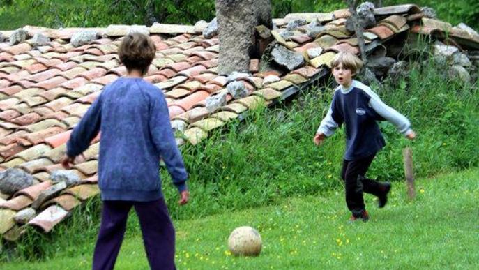 Pla general de dos nens jugant a pilota a casa seva, a Vallcebre