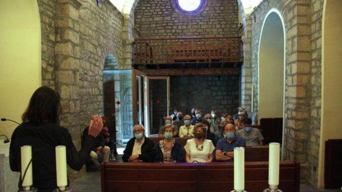 Pla obert d'un grup de visitants a l'interior de l'església de Santa Maria d'All, a Isòvol (Cerdanya), i la seva guia d'esquenes explicant els elements patrimonials del temple.