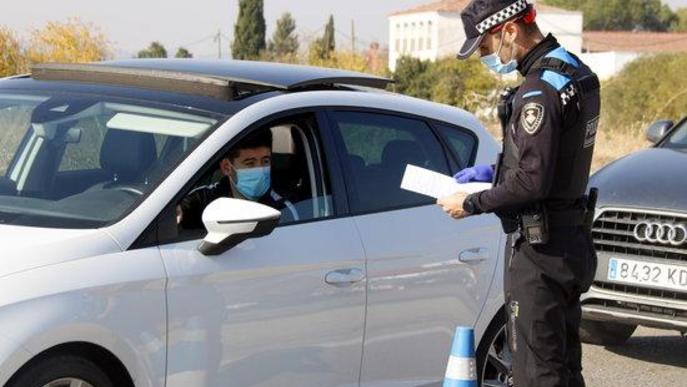 Pla mitjà d'un agent de la Guàrdia Urbana mirant el paper justificant de mobilitat d'un conductor a un control a la N-230 direcció Lleida