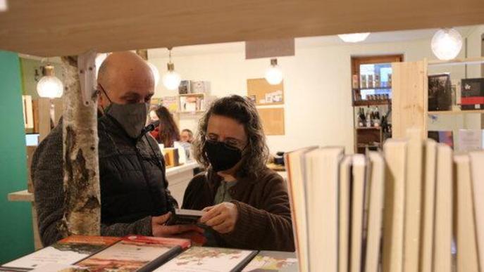 Pla mig de dos clients a la llibreria NaturaLlibres d'Alins fullejant algun llibre
