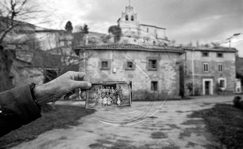 L'autor de l'exposició, Sergi Bernal, sosté una fotografia del mestre amb els alumnes davant de l'escola.