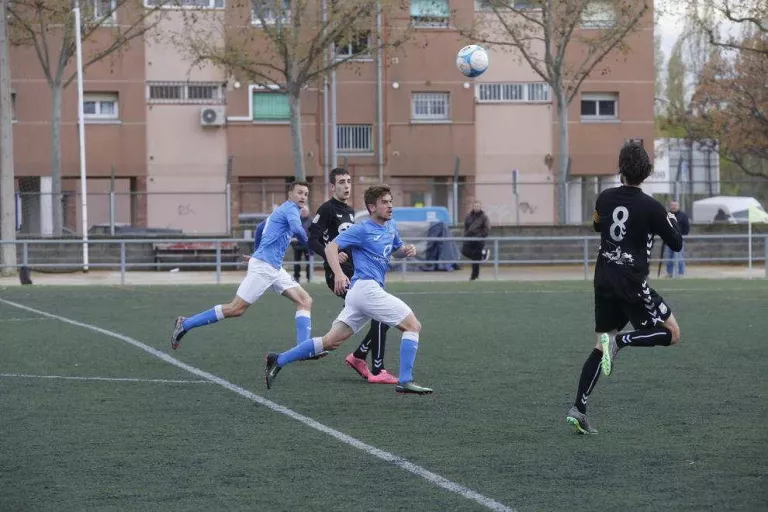 Diversos jugadors intenten controlar una pilota aèria en una jugada del partit.