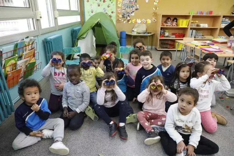 Els alumnes de P4, els ‘exploradors’, amb la tenda de campanya i els prismàtics que han construït.